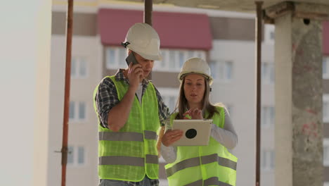 Supervisor-De-Un-Edificio-En-Construcción,-Un-Hombre-Discutiendo-Con-Una-Ingeniera-Diseñadora-Sobre-El-Progreso-De-La-Construcción-Y-Examina-Un-Plan-De-Construcción.